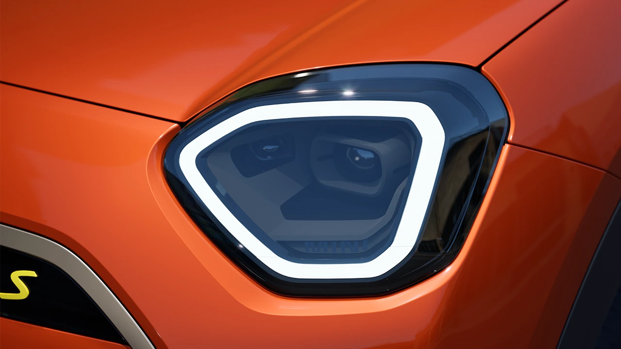 Vista detalhada do farol do MINI Aceman totalmente elétrico com luz branca acesa.