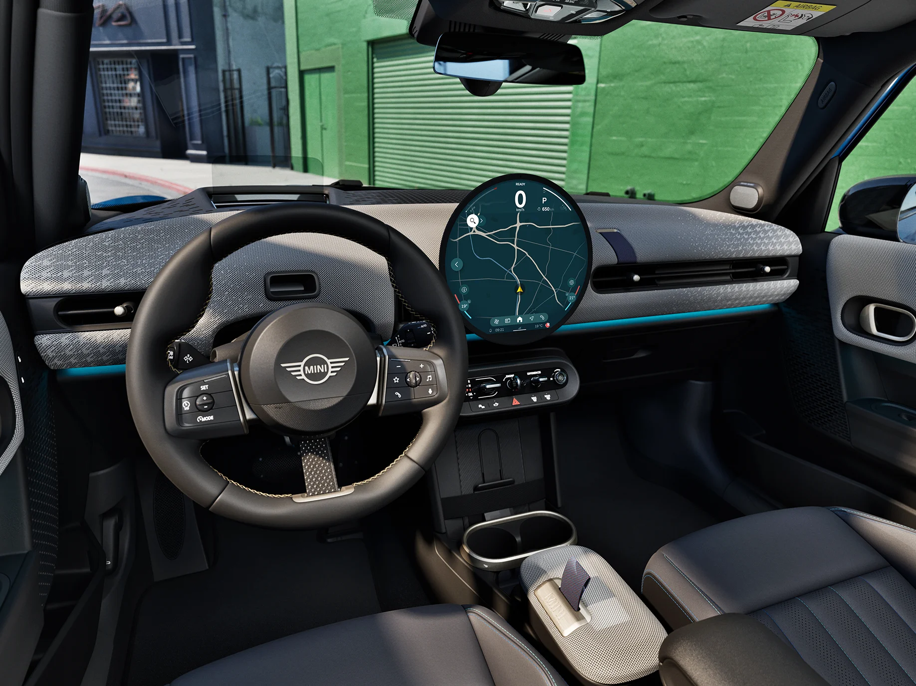 Vista interna do MINI Cooper 5 portas com foco no volante, no painel de instrumentos e na unidade de interação.