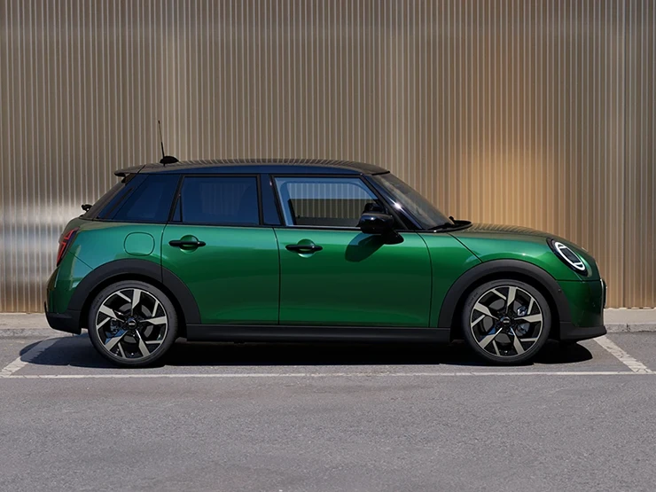 Vista lateral do MINI Cooper 5 portas na cor British Racing Green, com teto em preto, estacionado.