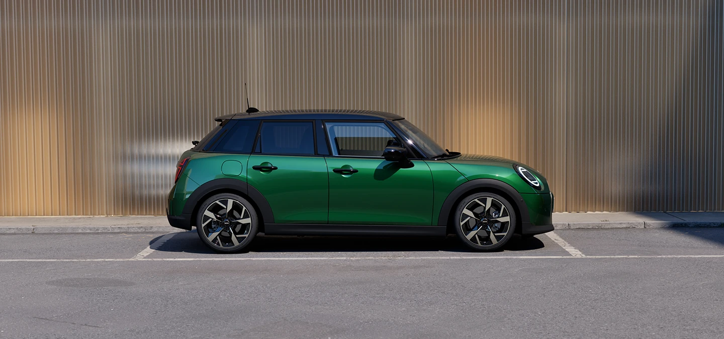 Vista lateral do MINI Cooper 5 portas na cor British Racing Green, com teto em preto, estacionado.