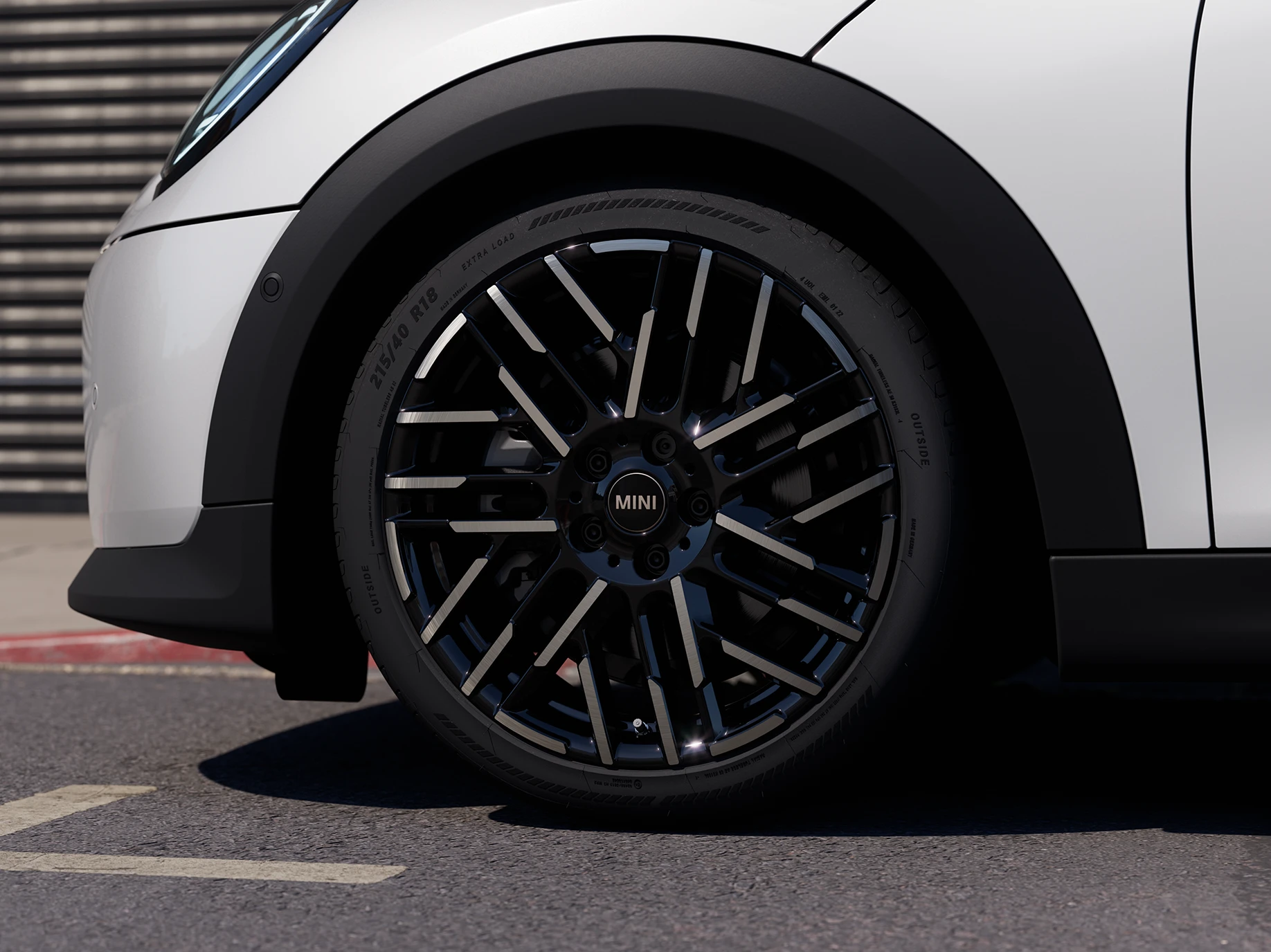 Imagem em close-up do MINI Cooper 5 portas na cor Nanuq White com rodas bicolores Night Flash Spoke.