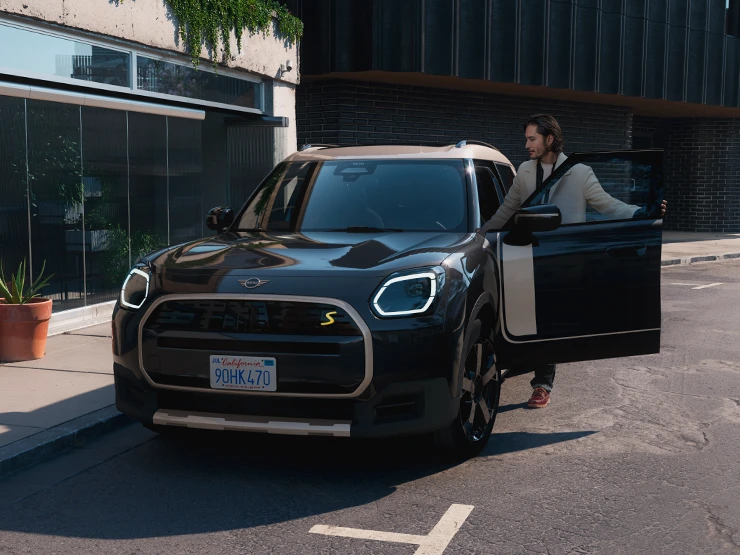 Vista frontal do MINI Countryman totalmente elétrico em Midnight Black e Vibrant Silver Roof, em uma rua.