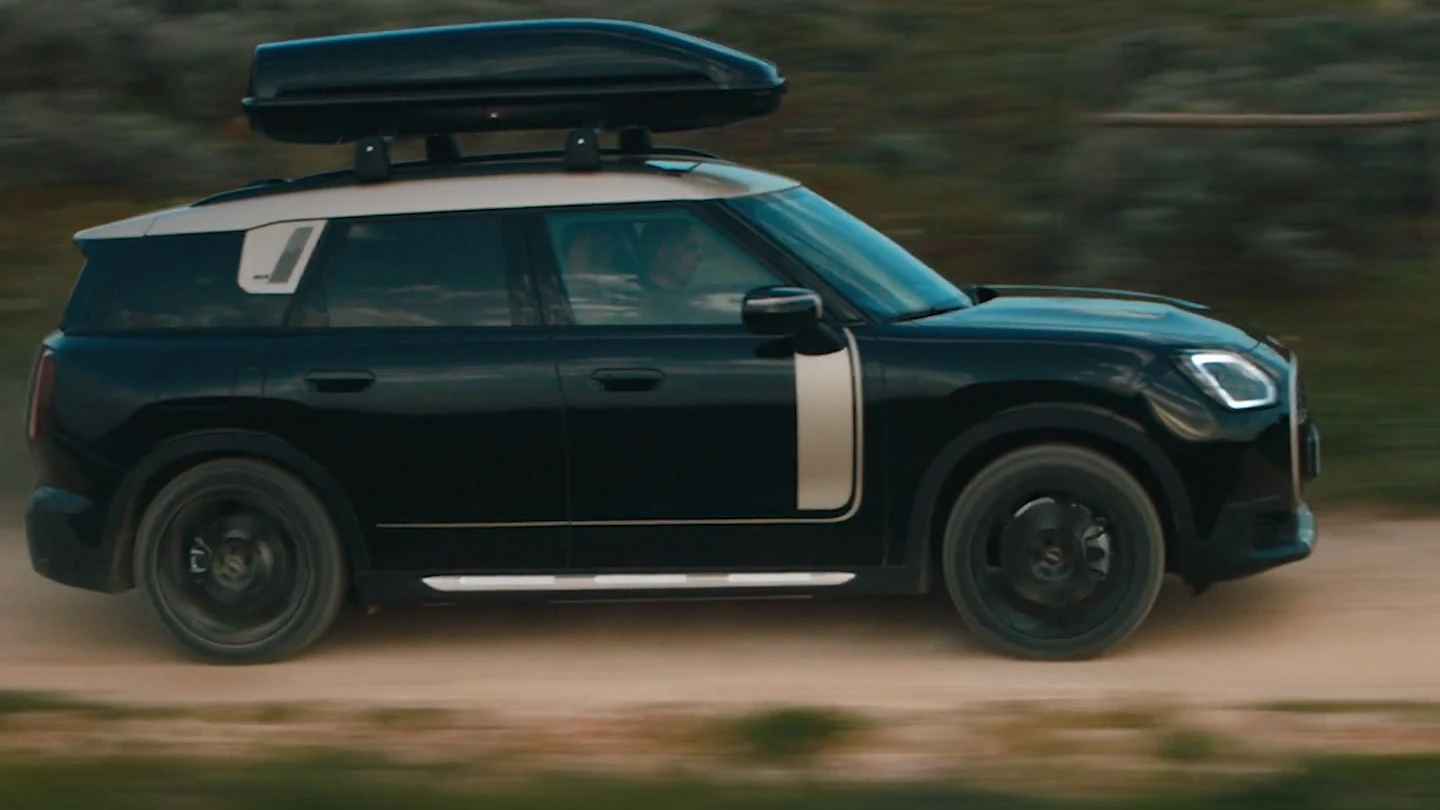 MINI Countryman na cor Midnight Black metálico com rodas John Cooper Works Runway Spoke de 19'' na cor preta, trafegando fora de estrada.