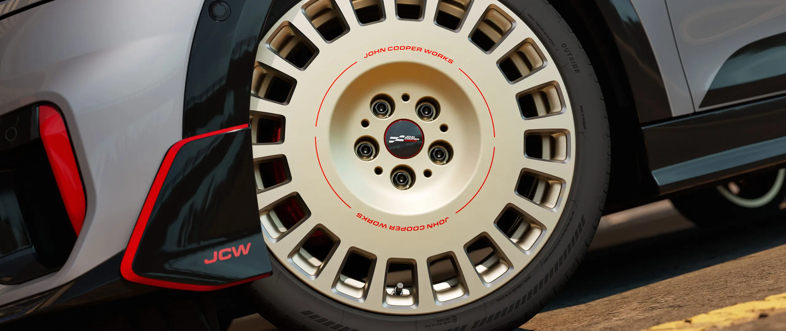 Close-up de uma roda JCW Rallye Spoke 964 de 18'' na cor Vibrant Silver Bicolor com acabamento diamantado e aleta dianteira.