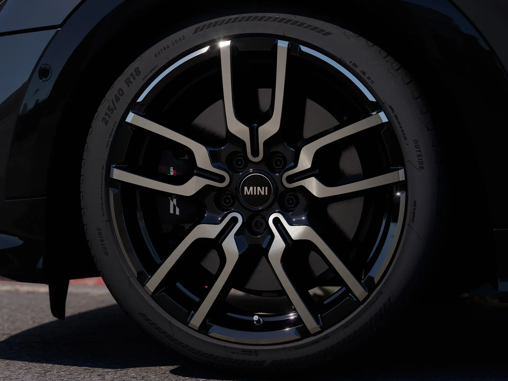 Close-up da roda de liga leve JCW Lap Spoke, destacando seu design exclusivo de raios abertos com acabamento em Jet Black.