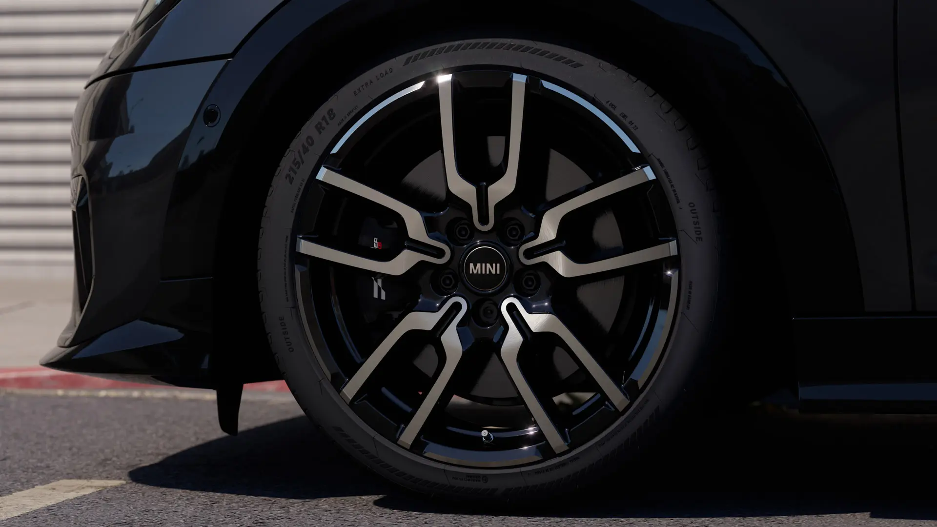 Close-up da roda de liga leve JCW Lap Spoke, destacando seu design exclusivo de raios abertos com acabamento em Jet Black.