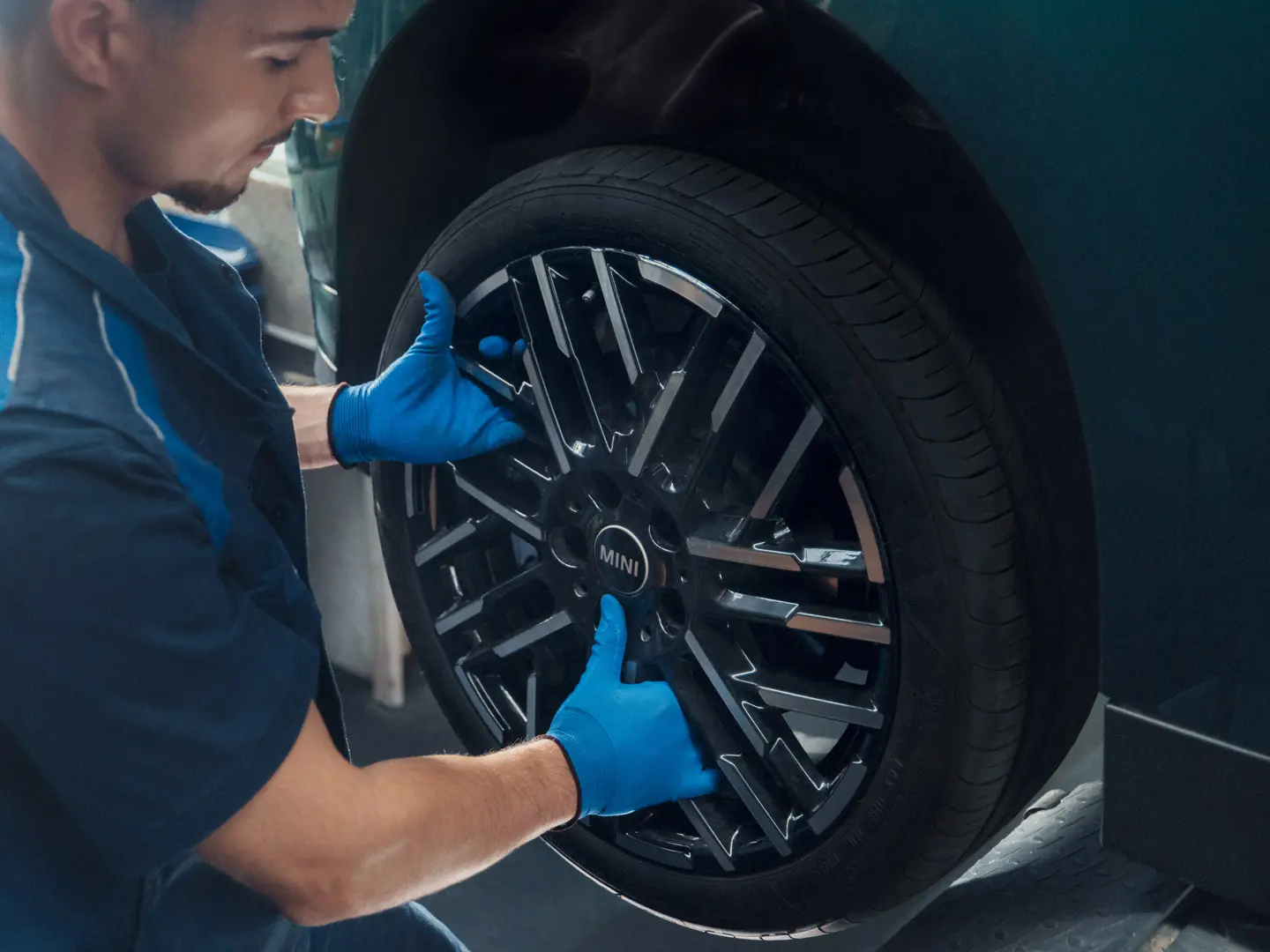 Um técnico de serviço da MINI instala uma roda de liga leve bicolor Night Flash Spoke de 18'' em um MINI Cooper Elétrico.