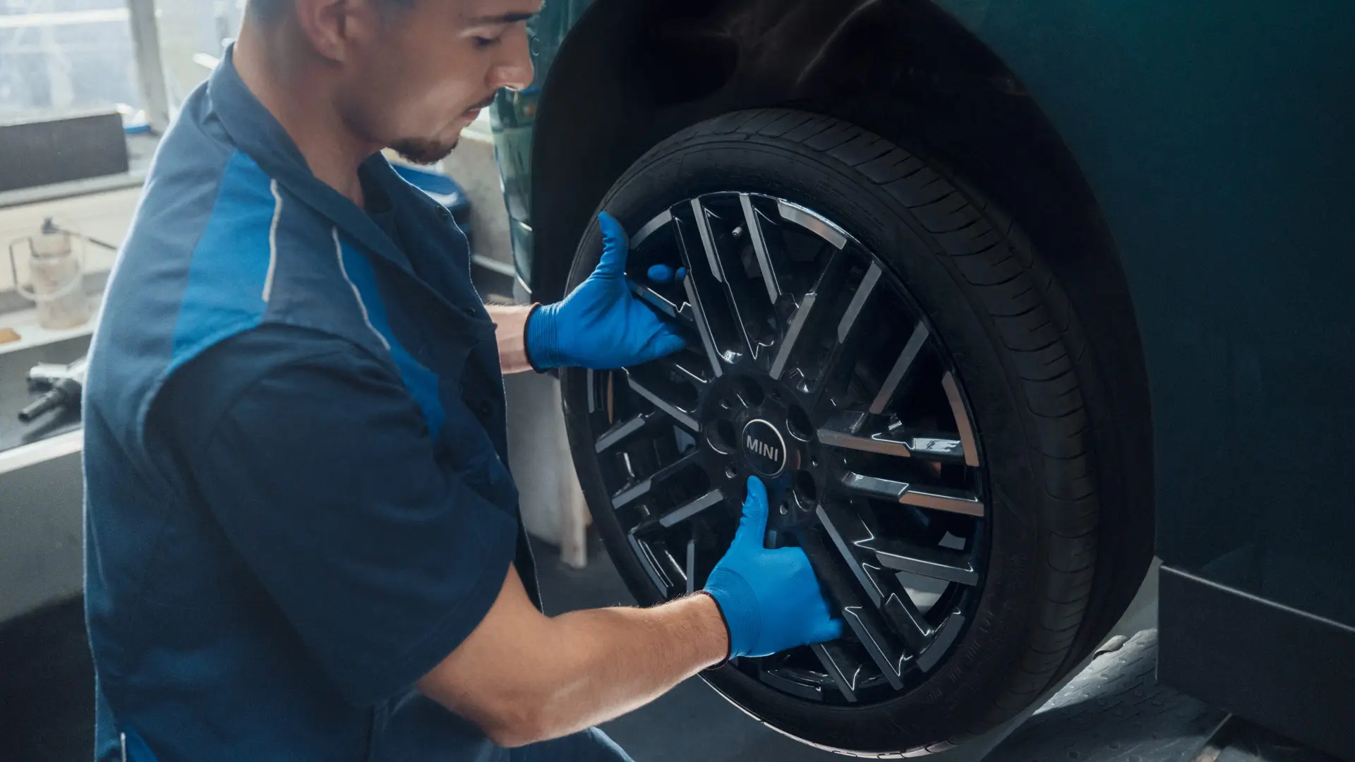 Um técnico de serviço da MINI instala uma roda de liga leve bicolor Night Flash Spoke de 18'' em um MINI Cooper Elétrico.