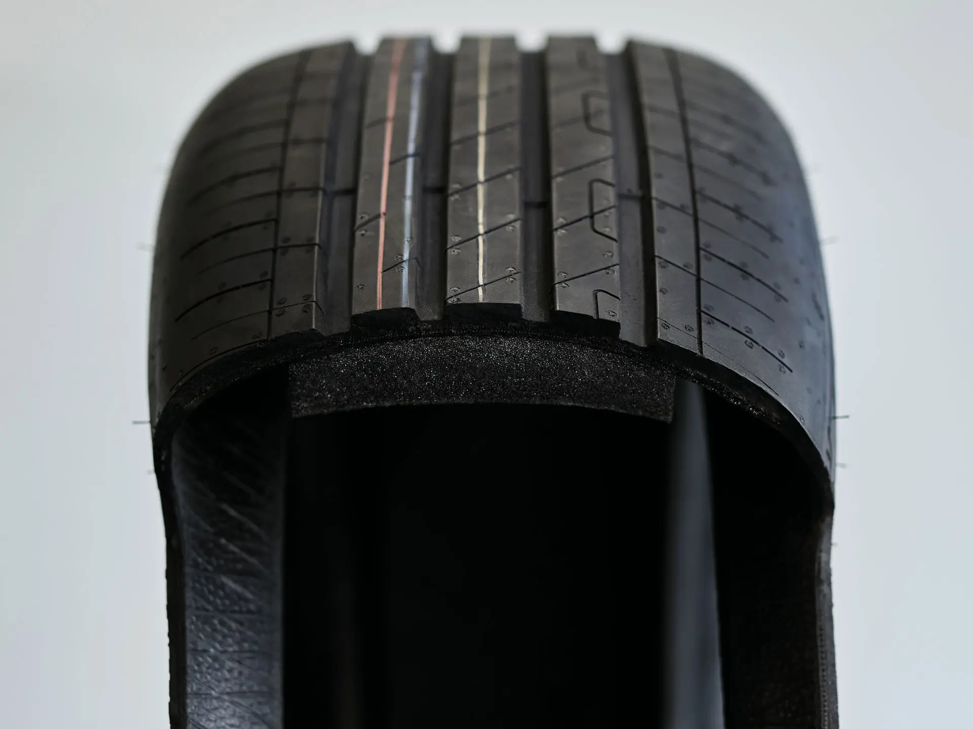 Vista em corte de um pneu run-flat mostrando a parede lateral espessa e resistente, que suporta o peso do veículo após um furo.
