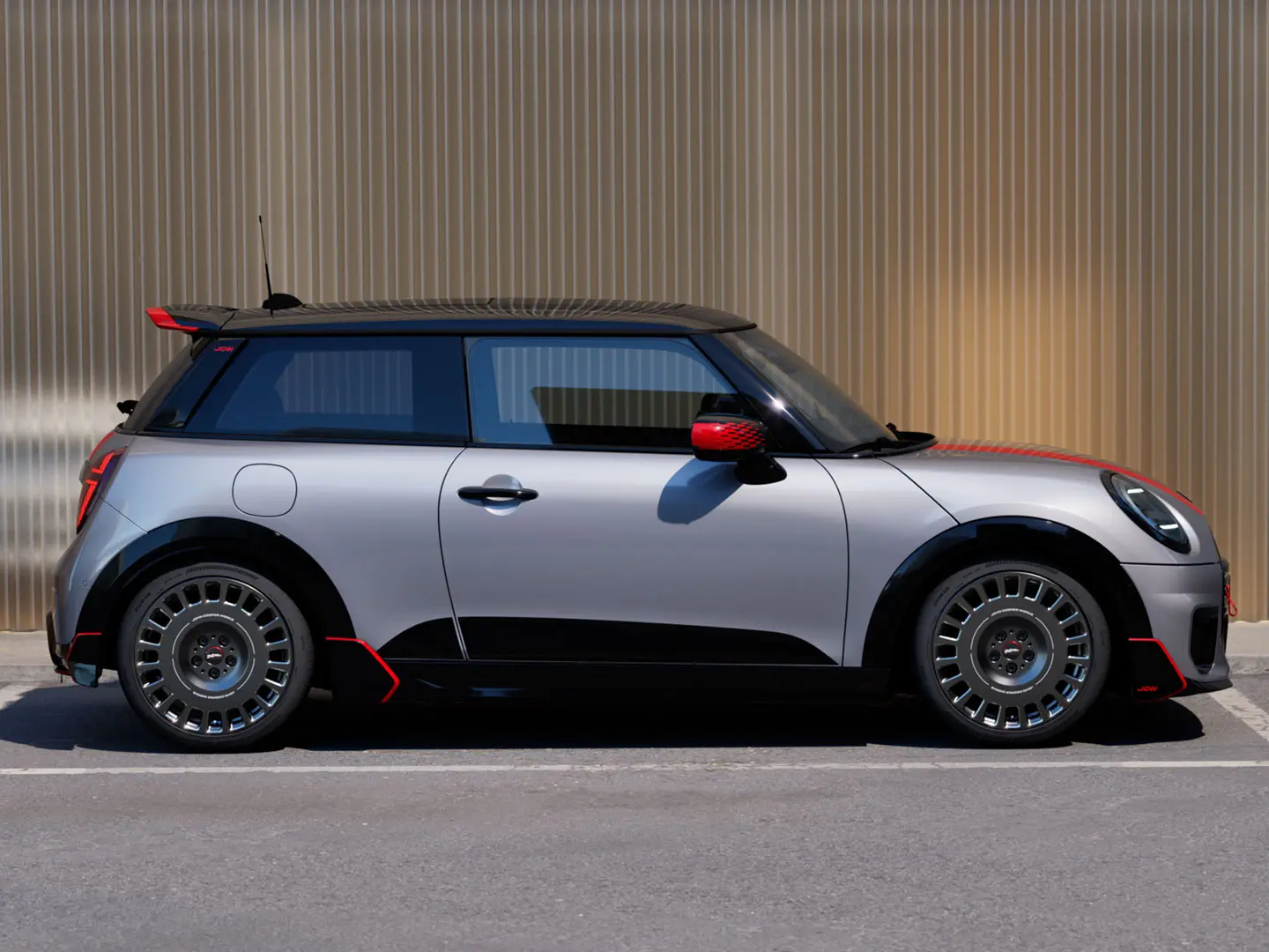 MINI Cooper 3 portas na cor Melting Silver com spoiler de teto John Cooper Works para aprimorar as propriedades aerodinâmicas - vista lateral.